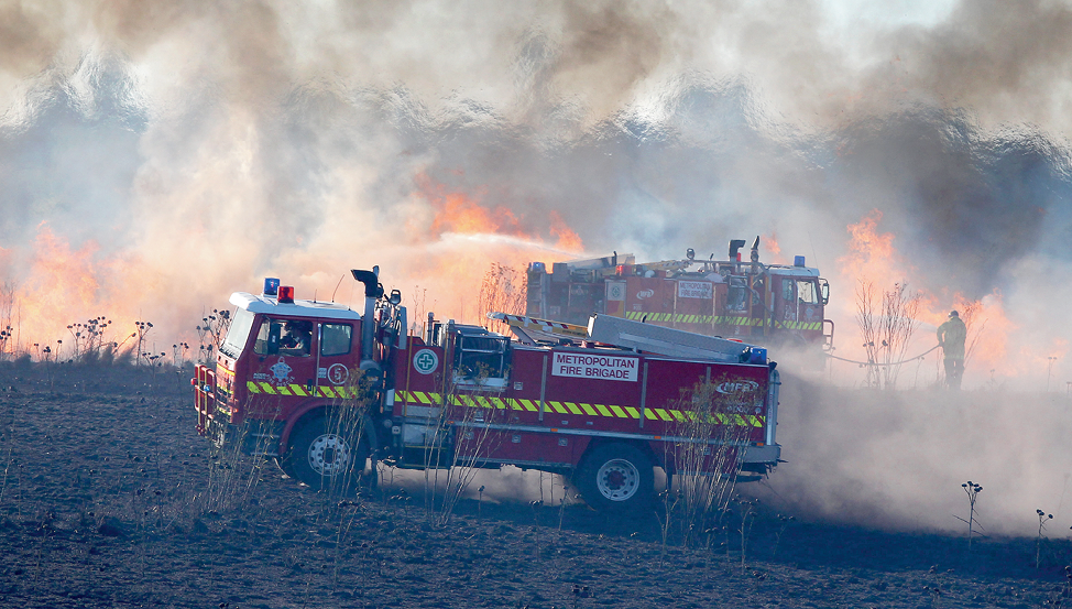 Photograph of emergency services vehicles and staff managing a grass fire