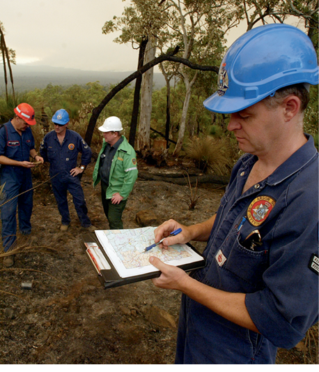 Photograph of an emergency services member looking at a map, with other members in the background
