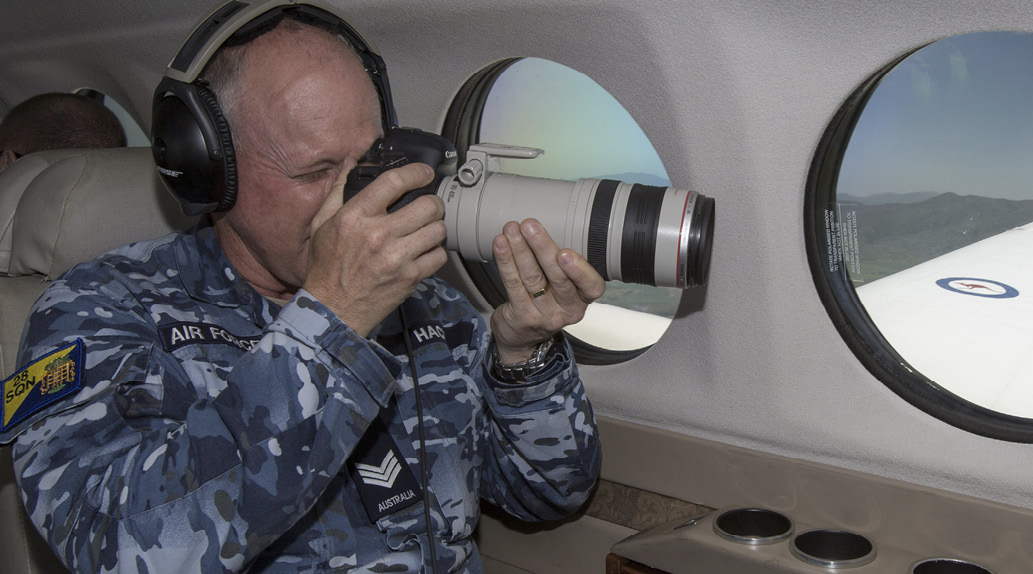 An image of an ADF member taking pictures from the window of an aeroplane.