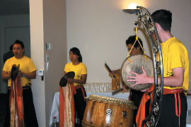 Four adults wearing yellow and black outfits playing various percussion instruments