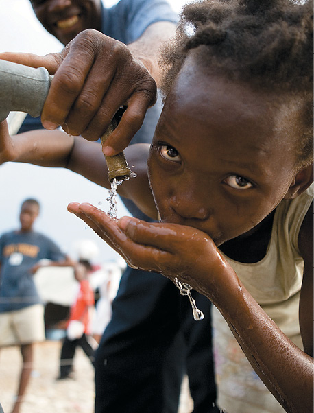 A Haitian child drinking water from a tap 