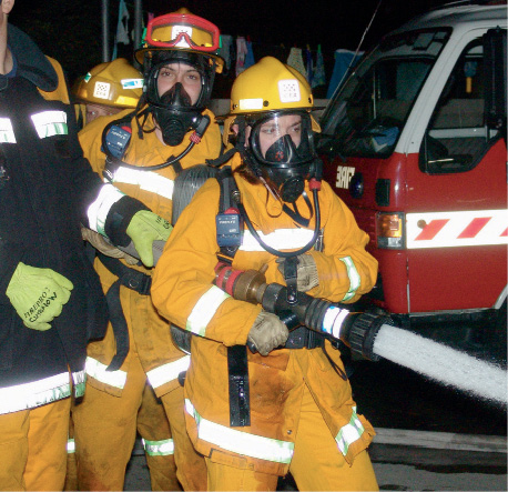 Three female firefighters in full safety gear operating a fire hose.