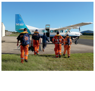 Five uniformed SES officers are walking towards a light aircraft parked on concrete tarmac.