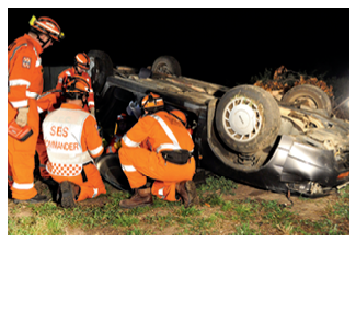 Several SES officers are assisting the occupants of an overturned car at night.