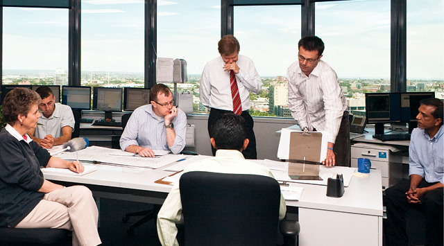 Photograph of people standing around and sitting at a desk, talking about disaster charts.