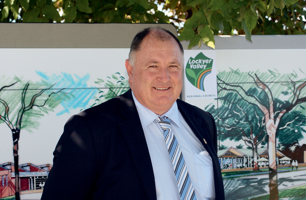 A photograph of Mayor Steve Jones, standing in front of drawings of trees and buildings.
