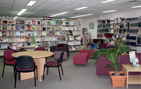 A large room lined with bookshelves, with tables, chairs and armchairs.