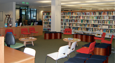 A large room lined with bookshelves, with chairs and tables