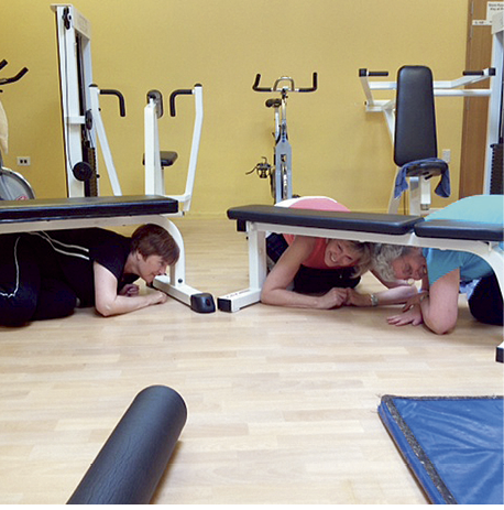 Photograph of people in a gym seeking cover under large gym equipment