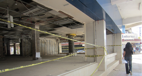 The ground floor of a large empty commercial building with no internal fitout, windows or doors. Yellow warning tape spans the external openings.
