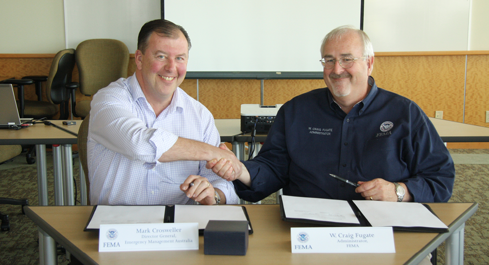 Mark Crosweller, Director General, Emergency Management Australia shakes hands with the United States Federal Emergency Management Agency’s Administrator, Craig Fugate as they sign an agreement.