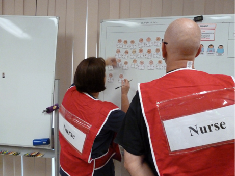 Two nurses use a whiteboard for complex incident response planning.