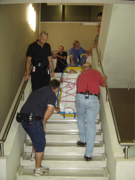 A Nursing team practicing carrying a fixed stretcher down a flight of stairs.