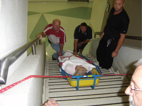 A stretcher is secured with ropes as a nursing team manoeuvre it down the stairs.