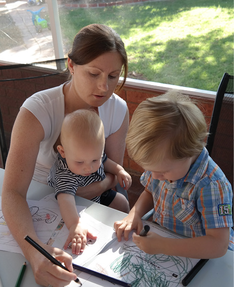 A photo of a parent playing games with her two children at home outside.