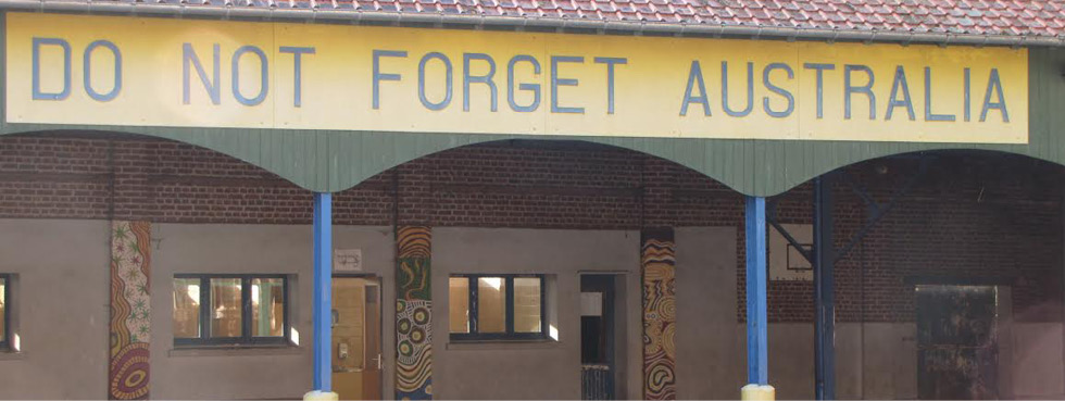A photo of the outside of a school. Across the top of a veranda, it says ‘Do not forget Australia’.