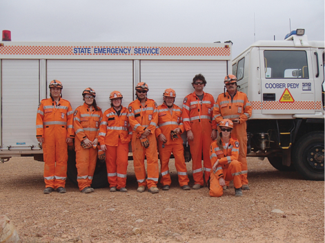 A photo of the volunteers (8 in total) standing in front of an SES building, and beside an SES emergency truck. The volunteers are wearing their orange SES uniforms.