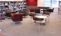 A photo of a sitting area, with small tables and some chairs among the bookshelves.