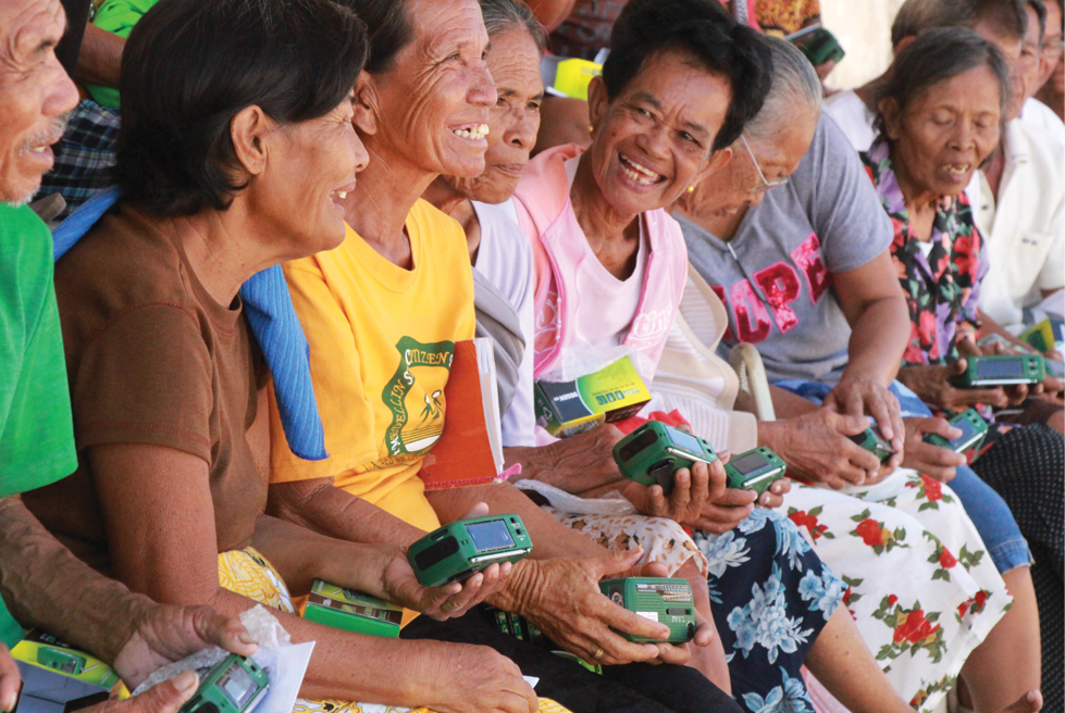 A photo of several smiling older people holding new radios.
