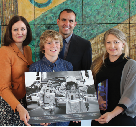 Sarah Henderson MP with Award winner Rebecca Hosking, teenager Elliot Rankin and Captain Andrew Rankin, holding a large print of the winning photograph.