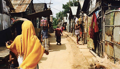 A photo of a street in a slum, with dirt roads and very rundown buildings.