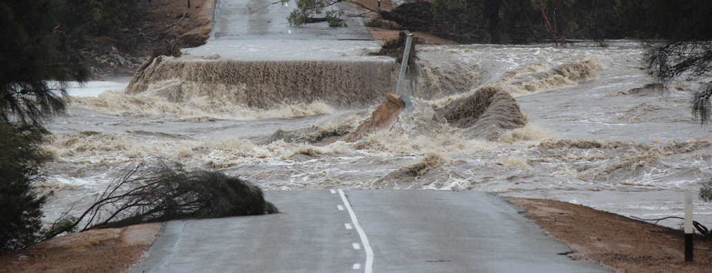 Image of a road broken and washed out from flood waters.